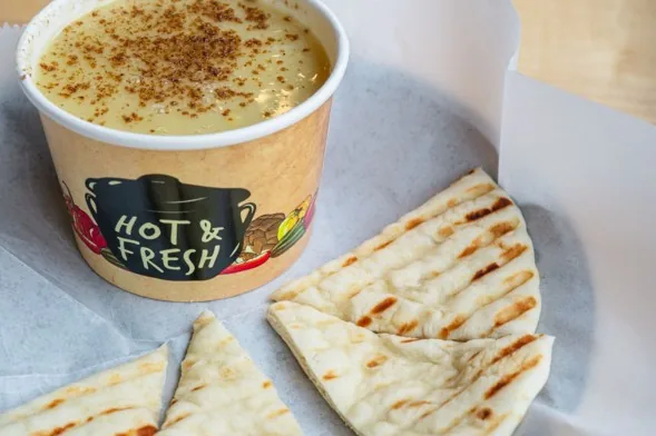 A cup of lentil soup served with warm grilled pita bread at Pita Corner